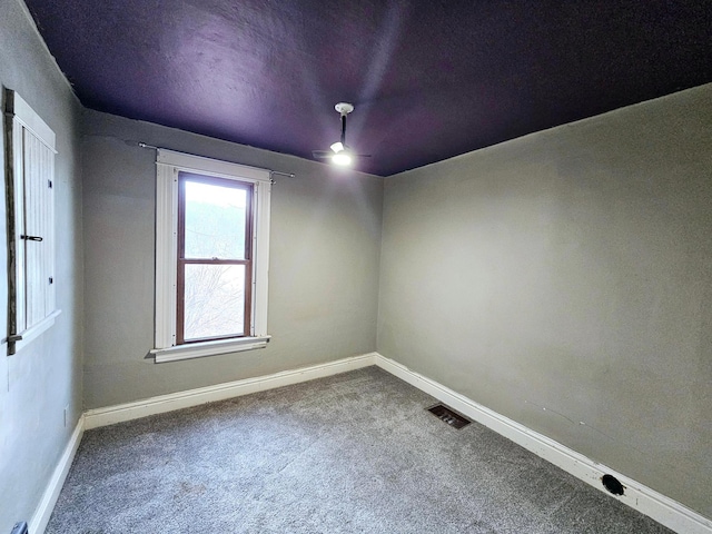 empty room with a ceiling fan, carpet flooring, visible vents, and baseboards