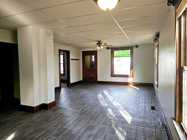 empty room featuring baseboards, a paneled ceiling, dark wood-type flooring, and ceiling fan