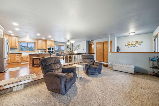 living area with light wood-style flooring, baseboard heating, and recessed lighting