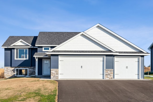 view of front facade featuring driveway, roof with shingles, an attached garage, and a front yard