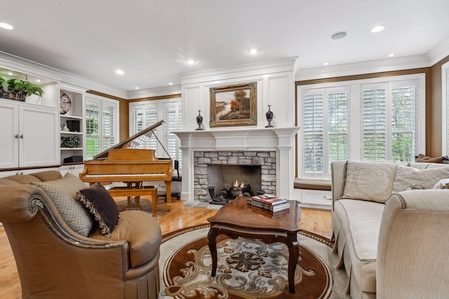 living room with light wood finished floors, a stone fireplace, recessed lighting, and ornamental molding