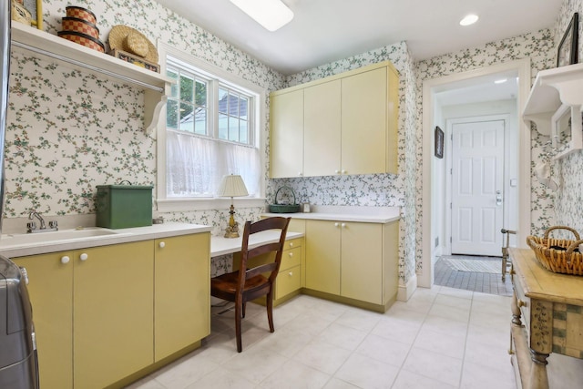 kitchen featuring a sink, cream cabinets, light countertops, and wallpapered walls