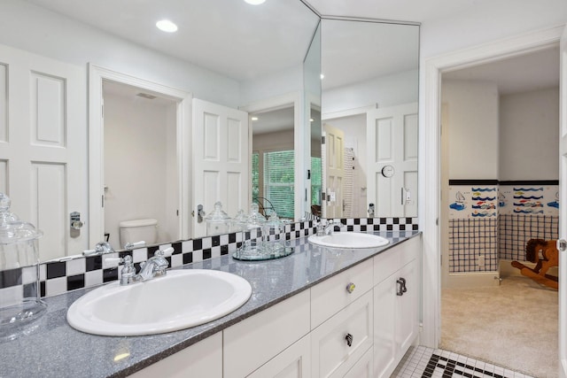 bathroom with a sink, toilet, recessed lighting, and double vanity