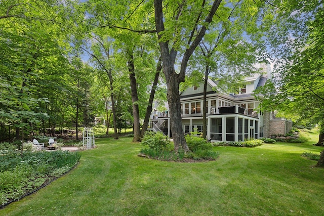 view of yard featuring a sunroom and an outdoor fire pit