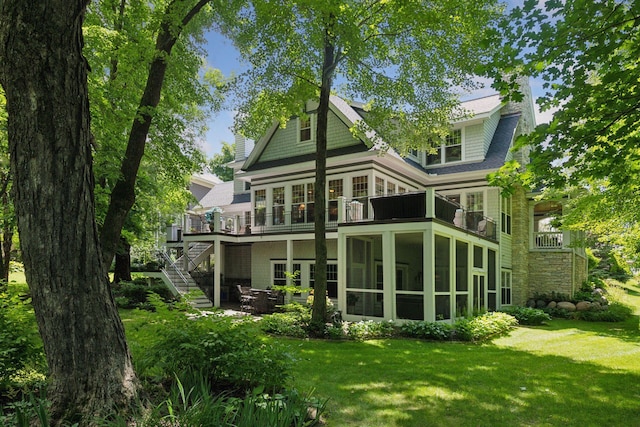 rear view of house featuring a lawn, stairs, and a sunroom