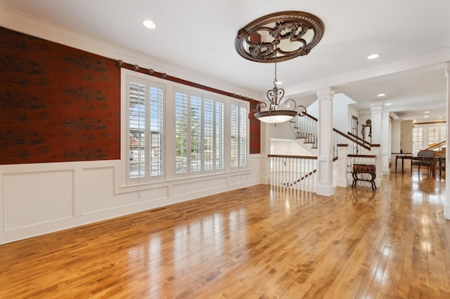 interior space featuring stairs, hardwood / wood-style floors, decorative columns, wainscoting, and a decorative wall