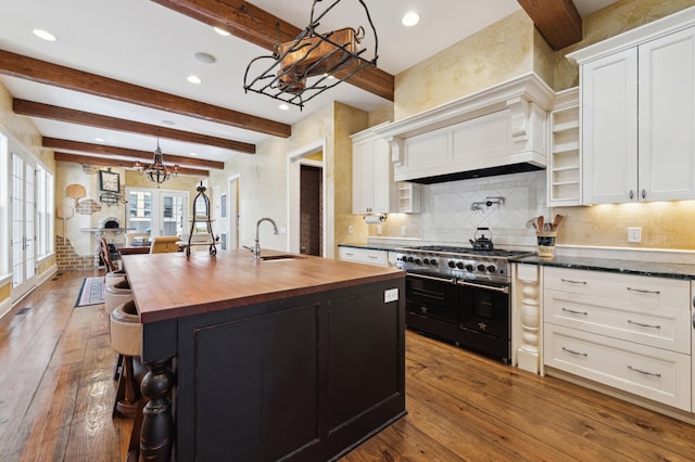 kitchen featuring double oven range, dark wood-style flooring, a sink, wood counters, and white cabinetry