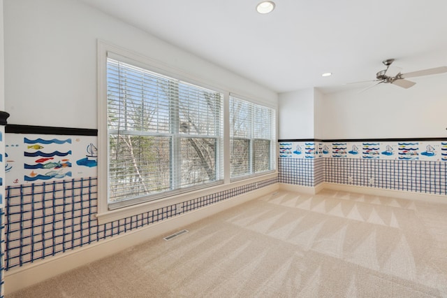 carpeted spare room featuring wainscoting, visible vents, recessed lighting, and a ceiling fan