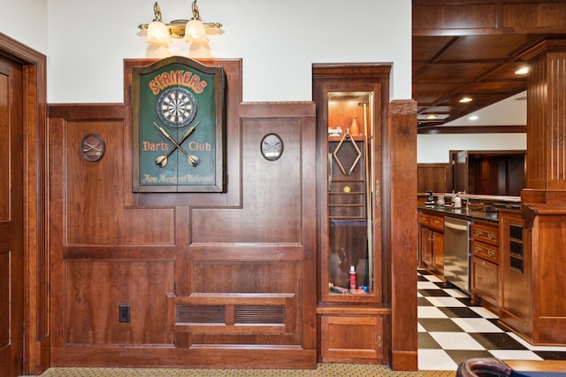 details featuring wooden walls, an inviting chandelier, wainscoting, dishwasher, and tile patterned floors