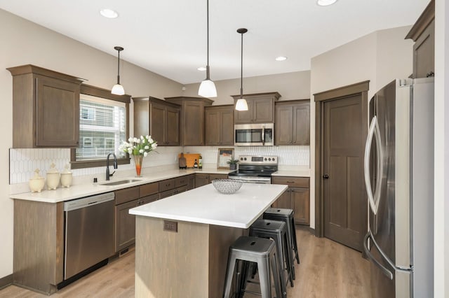 kitchen featuring light wood-style flooring, a sink, tasteful backsplash, a kitchen island, and stainless steel appliances