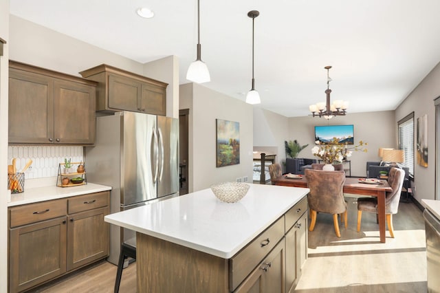 kitchen with a kitchen island, open floor plan, pendant lighting, light countertops, and light wood-type flooring