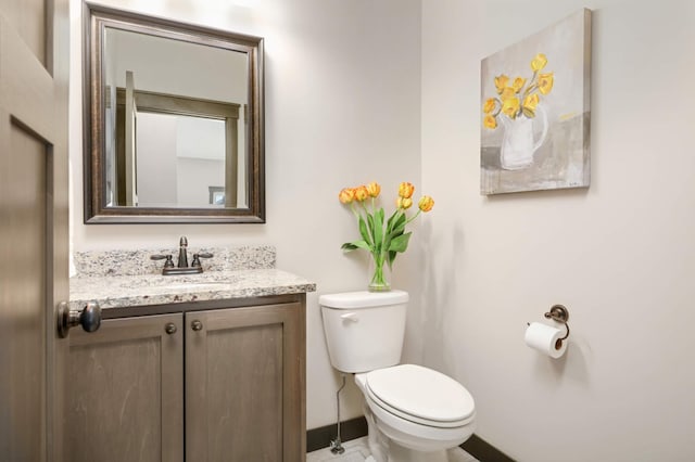 bathroom featuring toilet, vanity, and baseboards