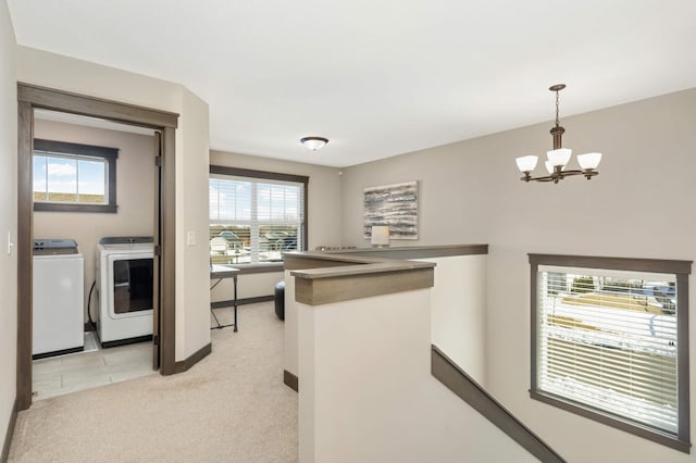 kitchen with washing machine and clothes dryer, pendant lighting, light carpet, a peninsula, and a notable chandelier