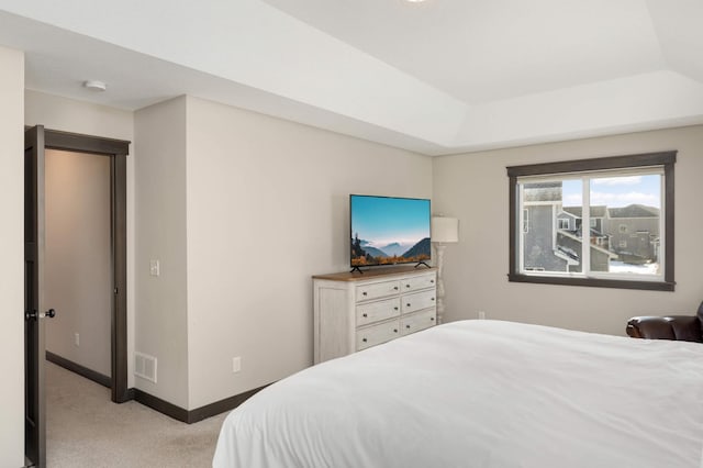 bedroom featuring visible vents, light colored carpet, a raised ceiling, and baseboards