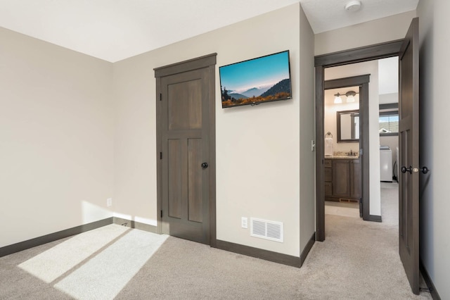 hallway featuring washer / dryer, baseboards, visible vents, and light carpet