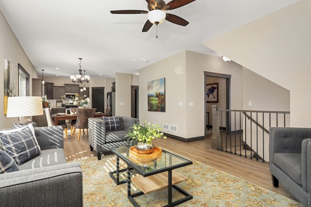 living area with light wood-type flooring, visible vents, ceiling fan with notable chandelier, recessed lighting, and baseboards