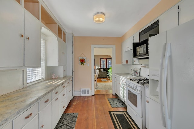 kitchen with light countertops, visible vents, white cabinets, light wood-type flooring, and white appliances