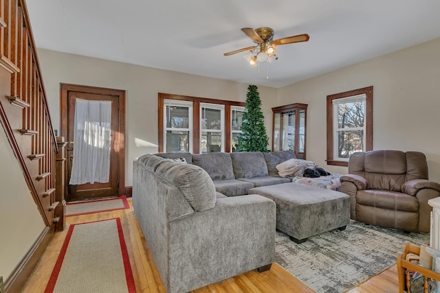 living area with light wood finished floors, ceiling fan, and stairway