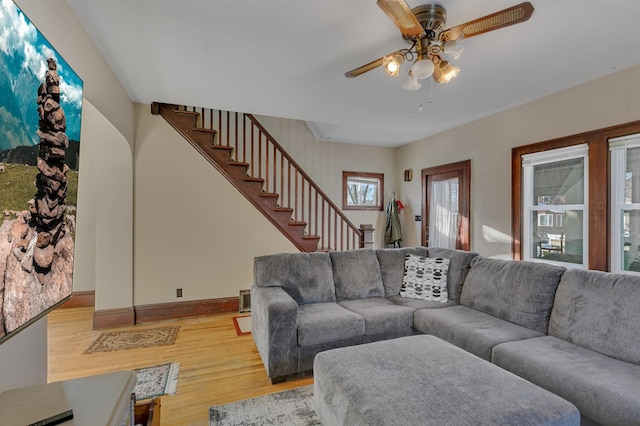 living room with ceiling fan, wood finished floors, visible vents, baseboards, and stairway