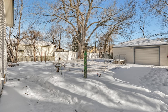 yard layered in snow with a garage, an outdoor structure, and fence