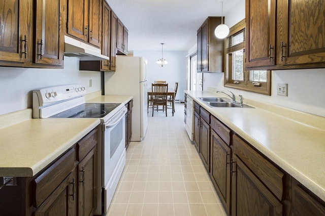 kitchen with white appliances, a sink, light countertops, under cabinet range hood, and pendant lighting