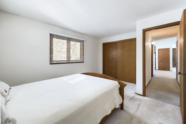 bedroom with light carpet, a textured ceiling, and a closet