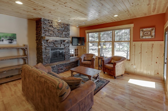 living room featuring wooden ceiling, a wainscoted wall, wood walls, a fireplace, and light wood finished floors