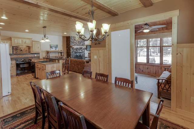 dining room featuring beam ceiling, wood walls, light wood-type flooring, and wood ceiling