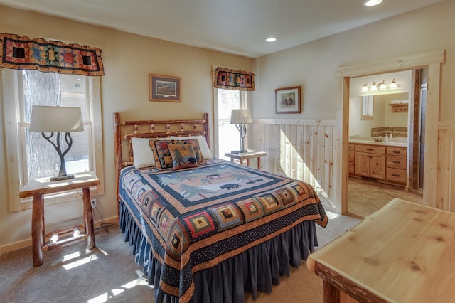 bedroom with ensuite bathroom, recessed lighting, a sink, and light colored carpet