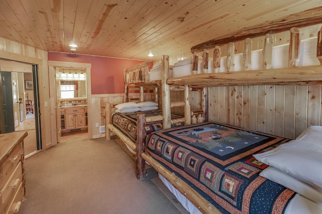 bedroom with a wainscoted wall, light colored carpet, connected bathroom, wood walls, and wooden ceiling