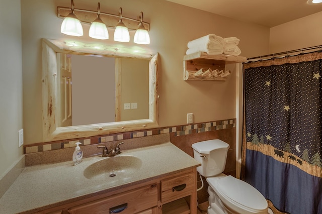 full bathroom featuring curtained shower, toilet, vanity, tile walls, and wainscoting