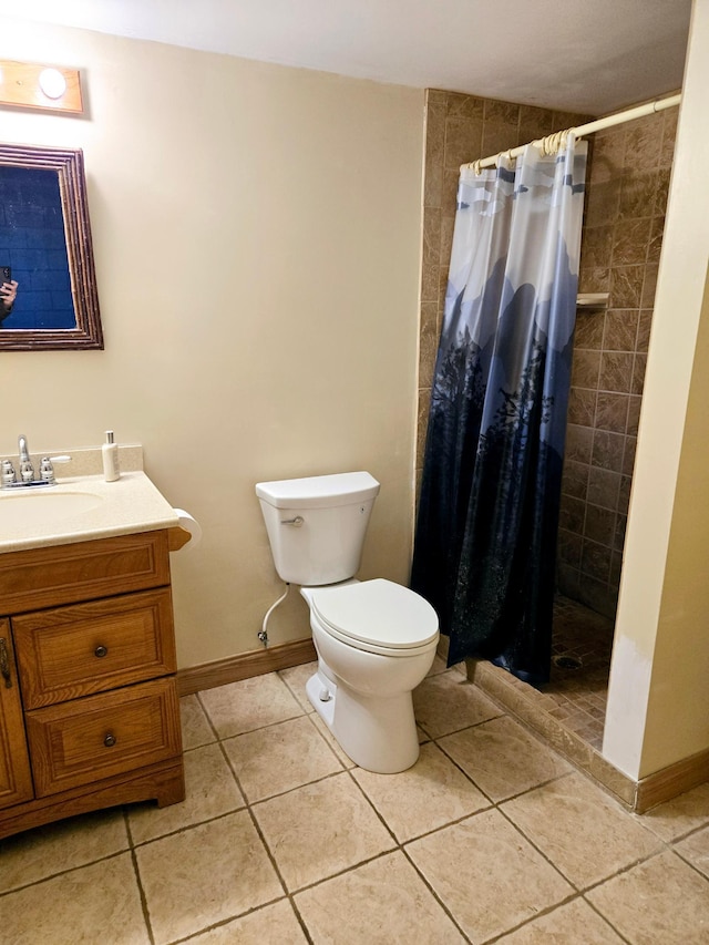 bathroom with tile patterned flooring, toilet, vanity, baseboards, and a stall shower