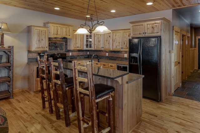 kitchen featuring wooden ceiling, hanging light fixtures, light brown cabinetry, black appliances, and a kitchen bar