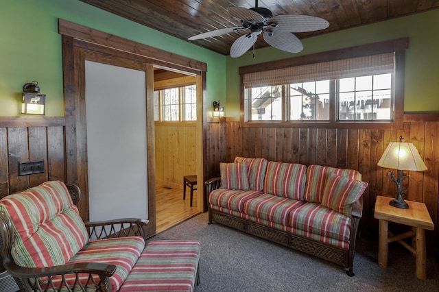 carpeted living area featuring a wainscoted wall and wooden walls