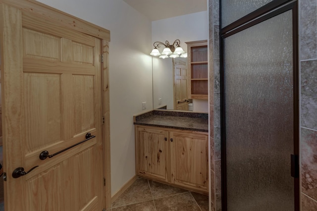 bathroom with a shower stall, tile patterned flooring, vanity, and baseboards