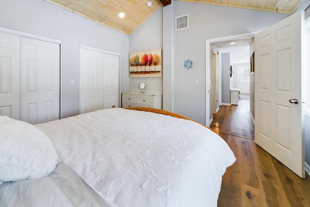 bedroom featuring visible vents, dark wood finished floors, two closets, and wood ceiling