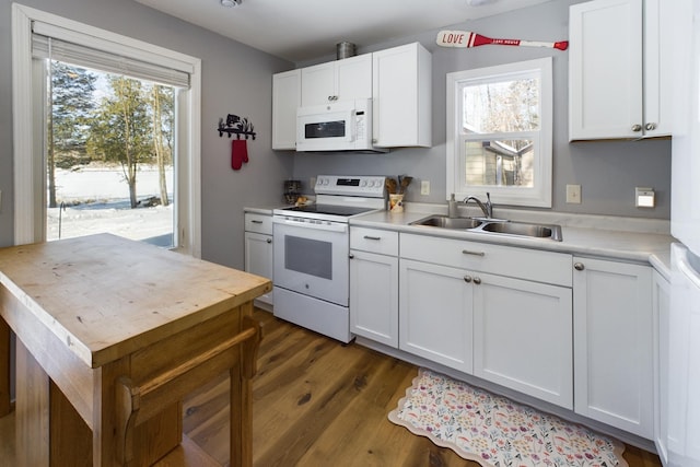 kitchen featuring white appliances, a sink, white cabinetry, light countertops, and dark wood finished floors