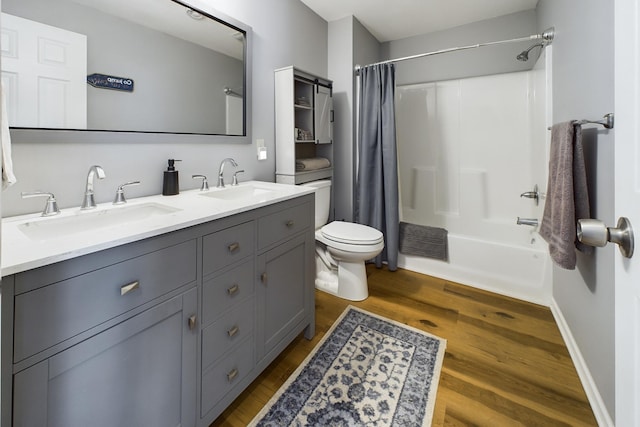 full bath with double vanity, shower / tub combo, toilet, wood finished floors, and a sink