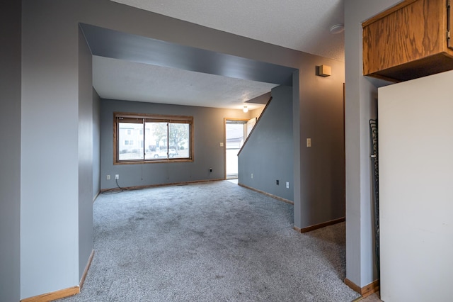 empty room with baseboards, a textured ceiling, and light colored carpet