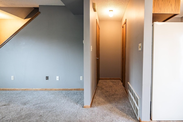 hall with baseboards, carpet, visible vents, and a textured ceiling