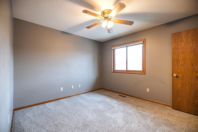 unfurnished room featuring light colored carpet, visible vents, a ceiling fan, a textured ceiling, and baseboards