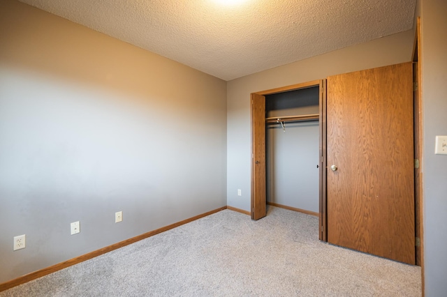 unfurnished bedroom with a closet, baseboards, a textured ceiling, and light colored carpet