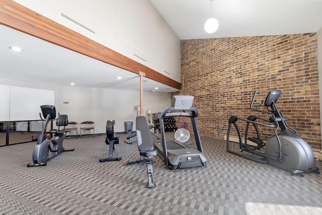 workout area with a towering ceiling, brick wall, recessed lighting, and light colored carpet