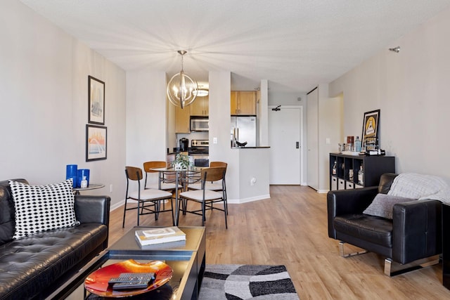 living area with baseboards, an inviting chandelier, and light wood-style flooring