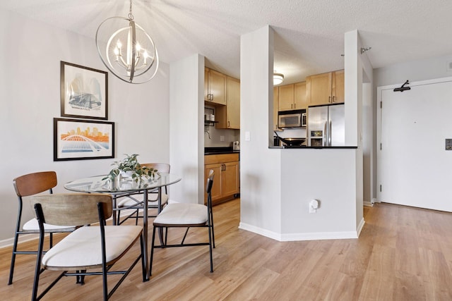 kitchen with light wood finished floors, light brown cabinets, stainless steel appliances, and dark countertops