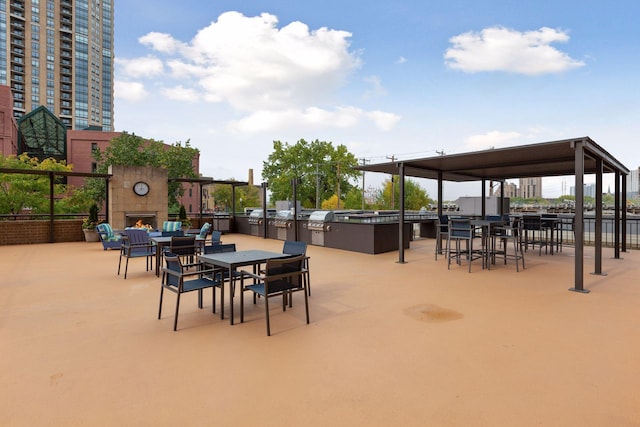 view of patio with a warm lit fireplace, an outdoor kitchen, and outdoor dining space