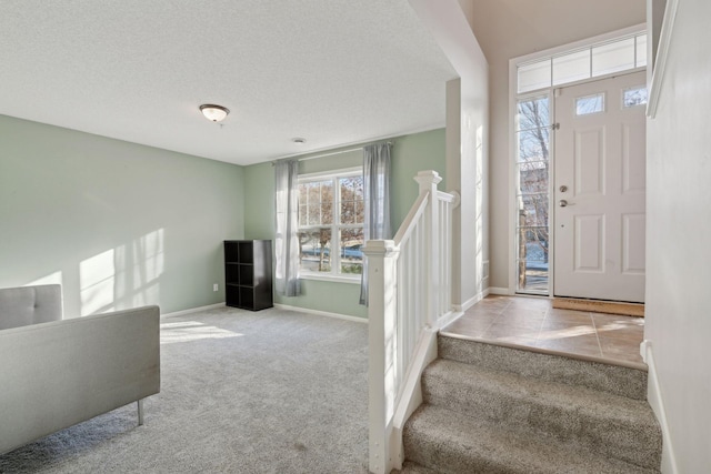 entrance foyer featuring light carpet, stairway, a textured ceiling, and baseboards