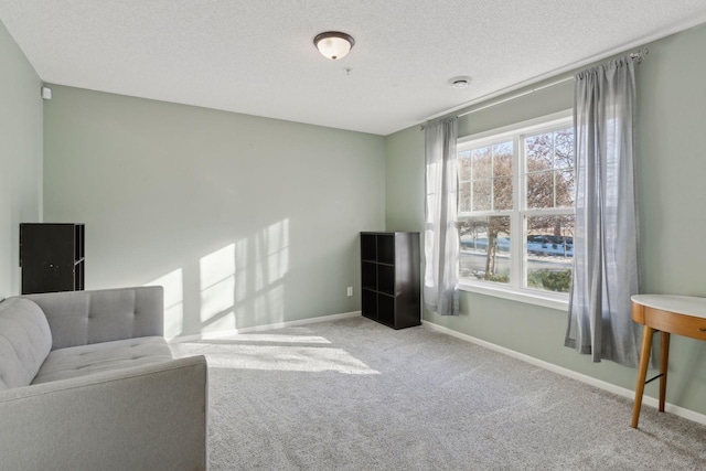 living area with a healthy amount of sunlight, baseboards, a textured ceiling, and light colored carpet