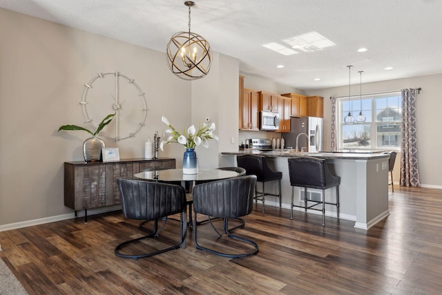 dining space featuring a notable chandelier, a textured ceiling, dark wood finished floors, recessed lighting, and baseboards