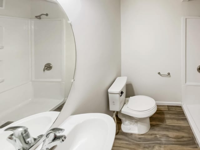 full bathroom with visible vents, baseboards, toilet, wood finished floors, and walk in shower